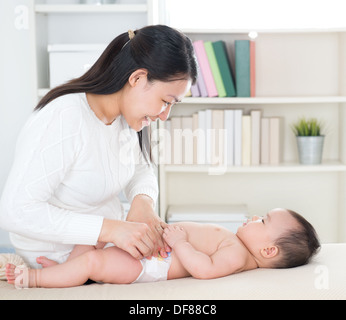 Asiatische Mutter ändern Windel Baby girl zu Hause. Stockfoto