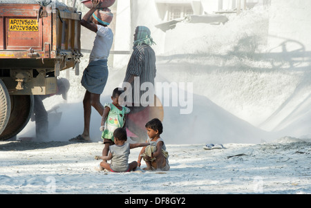 Indische Kinder spielen, umgeben von Staub, ungeschützt, auf einen Stein zerkleinern funktioniert. Andhra Pradesh, Indien Stockfoto