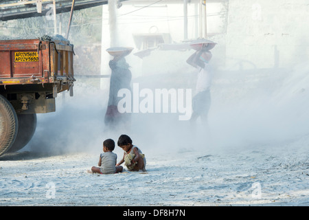 Indische Kinder spielen, umgeben von Staub, ungeschützt, auf einen Stein zerkleinern funktioniert. Andhra Pradesh, Indien Stockfoto