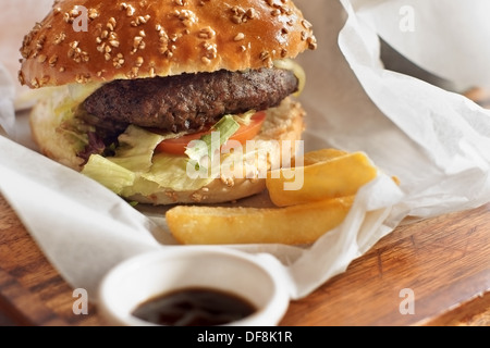 Gourmet Burger in einem gerissenen Weizen Brötchen mit geschmolzenem Käse Salat und Tomaten Stockfoto