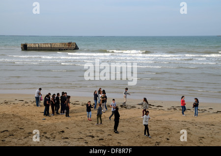 1944 d-Day in der Normandie: französische Jugendliche vor die Überreste der Mulberry-Hafen in Arromanches, Normandie. Stockfoto