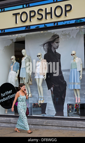 Eine junge Frau auf einem Handy zu sprechen, während sie im Topshop Store an der Princes Street in Edinburgh geht. Stockfoto