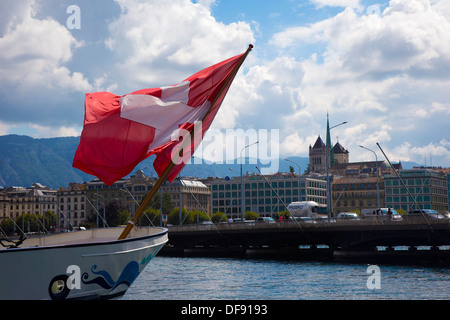 Schweizer Flagge, die von einem Boot in den Genfer See mit der Stadt im Hintergrund Stockfoto