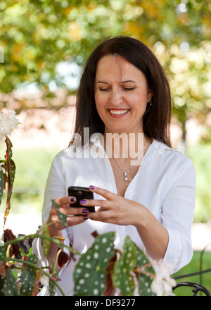 Mittlere gealterte Frau kaukasischen mit Smartphone im Garten Stockfoto
