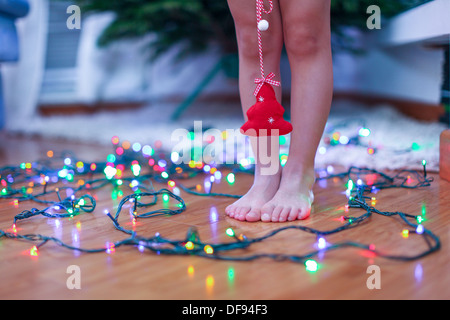 Kleinen roten Baum in den Händen der charmanten niedliche Mädchen bei hellen Lichtern Hintergrund Stockfoto