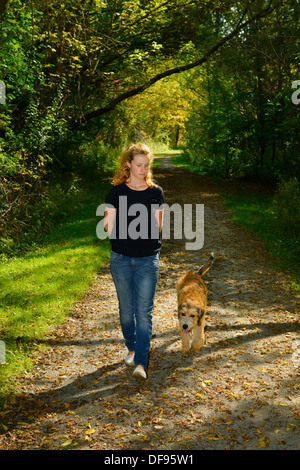 Junge Frau, die ihre Welpen aus der Leine gehen auf einem Pfad in den Wald ein Wald von Toronto Stockfoto