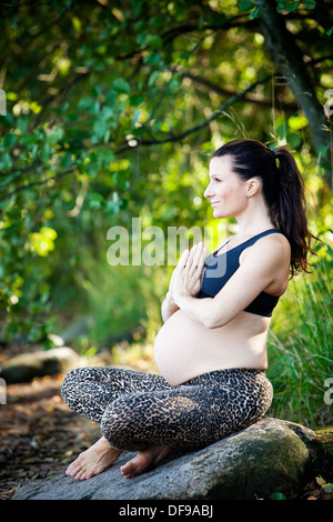 Schwangere Frau praktizieren Yoga am Strand Stockfoto