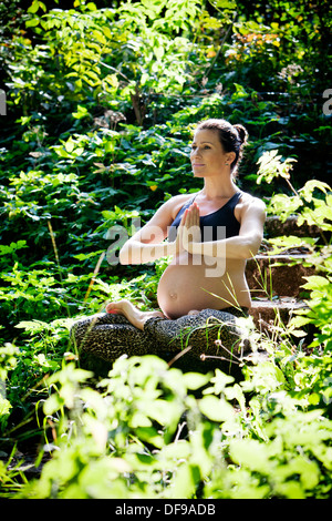 Schwangere Frau praktizieren Yoga am Strand Stockfoto