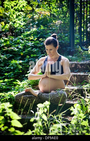 Schwangere Frau praktizieren Yoga am Strand Stockfoto