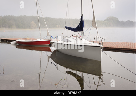 Zwei Boote im Nebel vor Anker Boardwalk am See Stockfoto