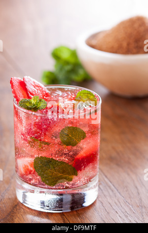Erdbeer Mojito serviert mit Limette und Eis auf Holztisch Stockfoto
