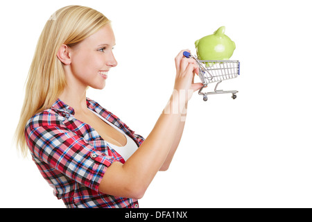 Junge blonde Frau hält einen Einkaufswagen mit einem Sparschwein Stockfoto