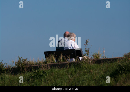 Rückansicht des ein älteres Ehepaar sitzt auf einer Bank Stockfoto