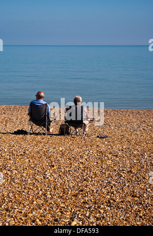 Rückansicht des ein älteres Ehepaar sitzt auf Strandkörbe Blick aus Meer Stockfoto