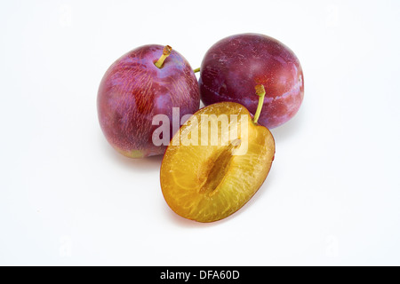 Ganze und halbe Pflaumen auf weißem Hintergrund. Stockfoto