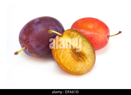 Ganze und halbe Pflaumen auf weißem Hintergrund. Stockfoto