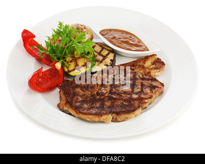 Gegrillte Steaks, gebackene Kartoffeln und Gemüse auf weißen Teller isoliert auf weißem Hintergrund. Stockfoto