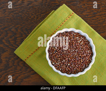 Kleine Schale rote Quinoa mit einer grünen Serviette auf einem braunen, hölzernen Tisch. Stockfoto
