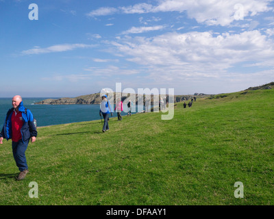 Insel von Anglesey Küsten Weg Wales Nordgruppe der Wanderer auf diesem legendären Weg über Porth Eilian mit Lynas Point Leuchtturm Stockfoto