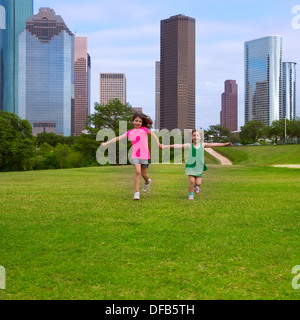 Zwei Schwester Mädchen Freunde laufen halten hand in urbanen moderne Skyline auf Rasen Stockfoto