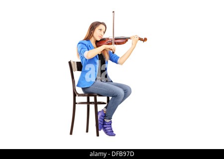 Lässige junge Frau sitzend auf einem Holzstuhl, Geige zu spielen Stockfoto