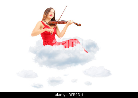 Junge Frau im roten Kleid mit dem Geigenspiel auf Wolken sitzen Stockfoto