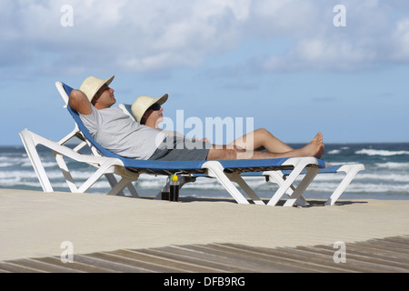 Paar zum Entspannen in der Sonne und Strand liege Stuhl Stockfoto