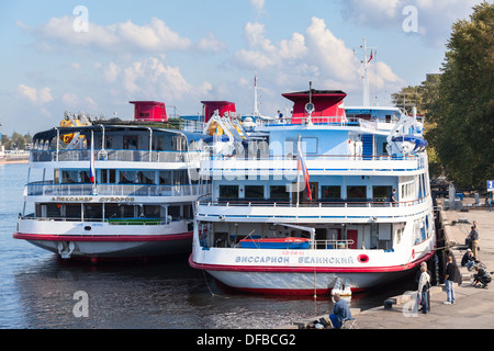 Sterns von zwei weißen Kreuzfahrtschiffe sind im Binnenhafen festgemacht. Sankt-Petersburg, Newa. Blauer Himmel mit Wolken. Stockfoto