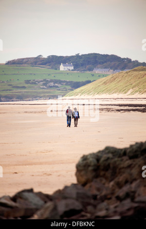 Mann und Frau, die Hand in Hand entlang Newborough Warren Strand, Isle of Anglesey, Wales, UK Stockfoto