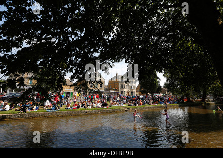 UK, Bourton-on-the-Water: Menschen spielen in der River Windrush. Bourton ist ein beliebtes Touristenziel in den Cotswolds. Stockfoto