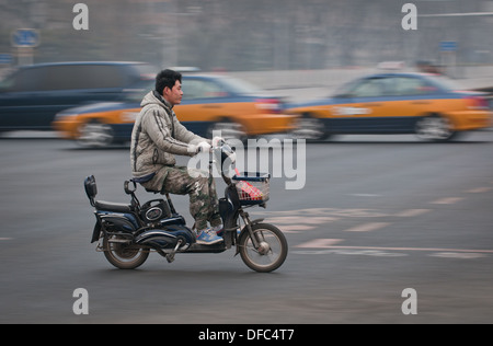 junge chinesische Mann reitet auf einem Moped in Peking, China Stockfoto