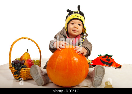 Herbst Baby Boy mit Biene Hut hält großen Kürbis vor weißem Hintergrund Stockfoto