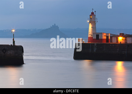 Morgendämmerung am Eingang zum Hafen von Newlyn in Cornwall England mit St Michaels Mount Silhouette im Hintergrund. Stockfoto