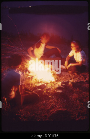 Schüler der Camdenton High School versammeln sich um ein Lagerfeuer auf einem Felsen und genießen den Blick auf den See bei einem geselligen Ausflug. Stockfoto