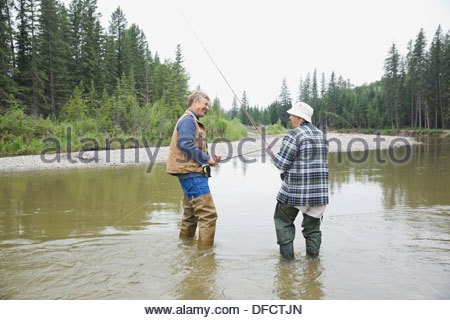 Vater und Sohn mit Angelruten stehen im Fluss