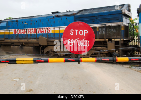 Stoppschild auf einer indischen Bahnübergang mit einem Zug vorbei. Andhra Pradesh, Indien Stockfoto