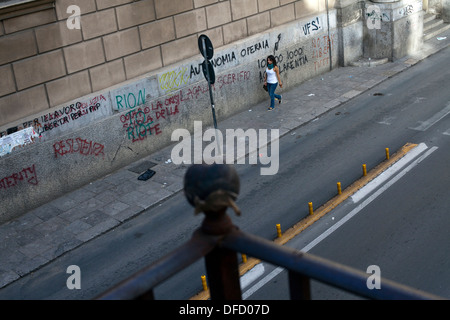 Ein Frauen-Wanderungen hinunter Via Maqueda an einer Mauer vorbei bedeckt Graffiti, Palermo, Italien Stockfoto