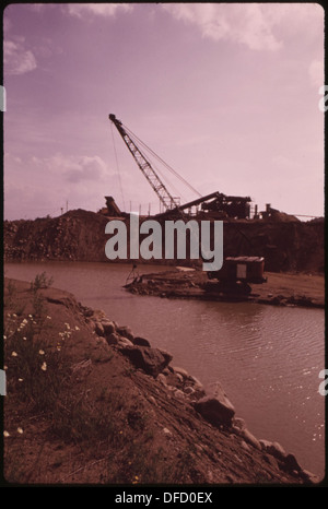 Eine Dragline-Maschine wird gezeigt, die Material für das Blacktop-Aufstoßen in der Nähe des Saranac Lake Village in New York, das sich im Adirondack Forest Preserve befindet, ausbaggert. Diese Maschinen spielen eine entscheidende Rolle bei der Vorbereitung von Materialien für den Straßenbau und die Instandhaltung in den bewaldeten Gebieten. Stockfoto