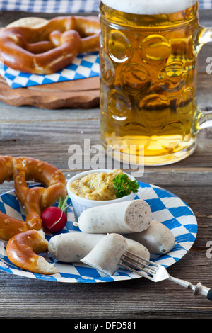 Oktoberfest-Menü mit Kalb Würstchen, Senf, Brezeln und ein kühles Bier auf einem rustikalen Holztisch Stockfoto