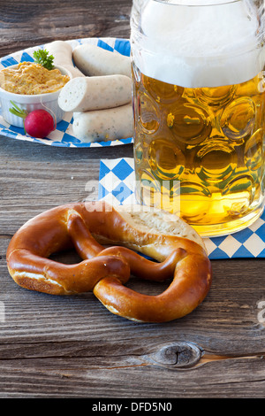 Ein kühles Bier im Seidel, eine Brezel im Vordergrund und im Hintergrund ein Pappteller mit Weißwurst und Senf Stockfoto