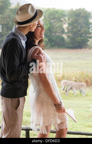 Paar in späten Zwanzigern auf Hochzeitsreise beobachten Zebras in Weide, Winelands, Western Cape, Stellenbosch, Südafrika Stockfoto