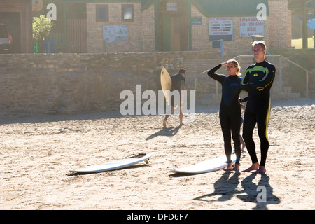 Hintergrundbeleuchtung Schuss der kaukasischen koppeln mit Surfboards stehen im Sand, die Wellen, Victoria Bay, Garden Route, Südafrika zu beobachten Stockfoto