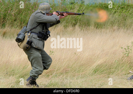 Ein Nachspieler im Zweiten Weltkrieg in der Uniform der deutschen Armee feuert sein Gewehr ab. Militärische Wiedererwirkung. Mündungsblitz. Das Heer Living History Gesellschaft Stockfoto