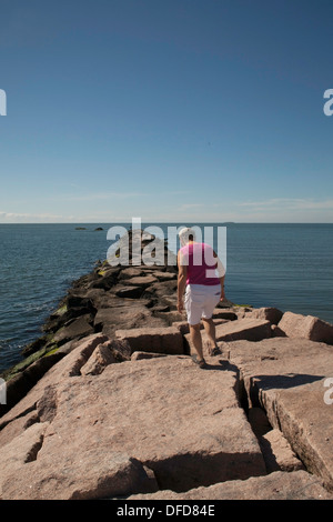 Im Spätsommer geht eine Frau entlang der Mole im Hammonasset Beach State Park, Madison, Connecticut. Stockfoto