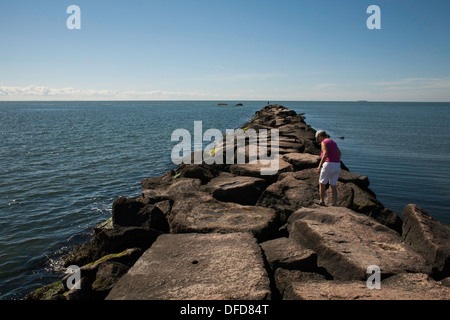 Im Spätsommer geht eine Frau entlang der Mole im Hammonasset Beach State Park, Madison, Connecticut. Stockfoto