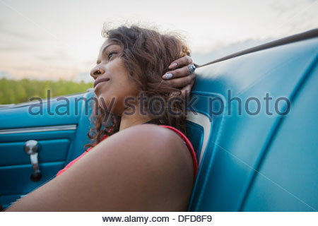 Nachdenkliche junge Frau sitzt im Cabrio