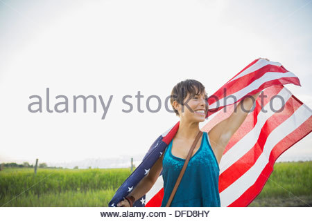 Junge Frau, die amerikanische Flagge draußen halten