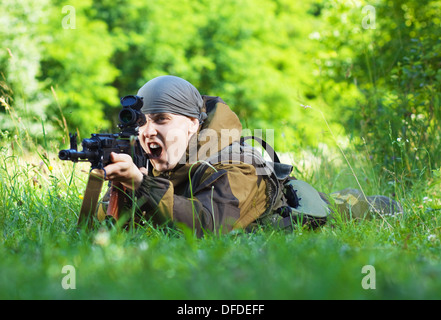 Soldat in Camouflage mit einer Kalaschnikow auf der Wiese liegend Stockfoto