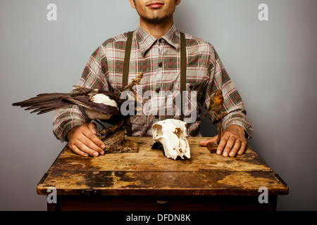 Junger Mann sitzt am Schreibtisch mit Präparatoren diorama Stockfoto