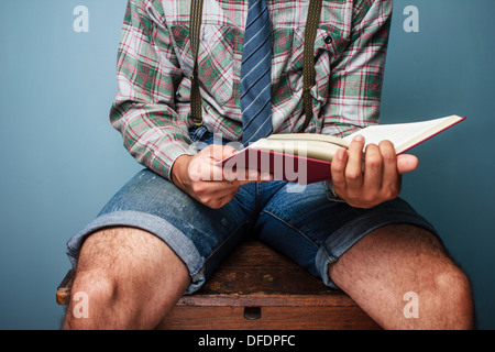 Mann am Schreibtisch sitzen und ein Buch zu lesen Stockfoto